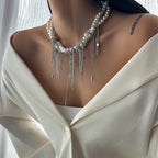 Pearl necklace with silver fringe on a person wearing a white blouse.