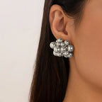 Silver ball cluster earring worn by a person with a neutral background
