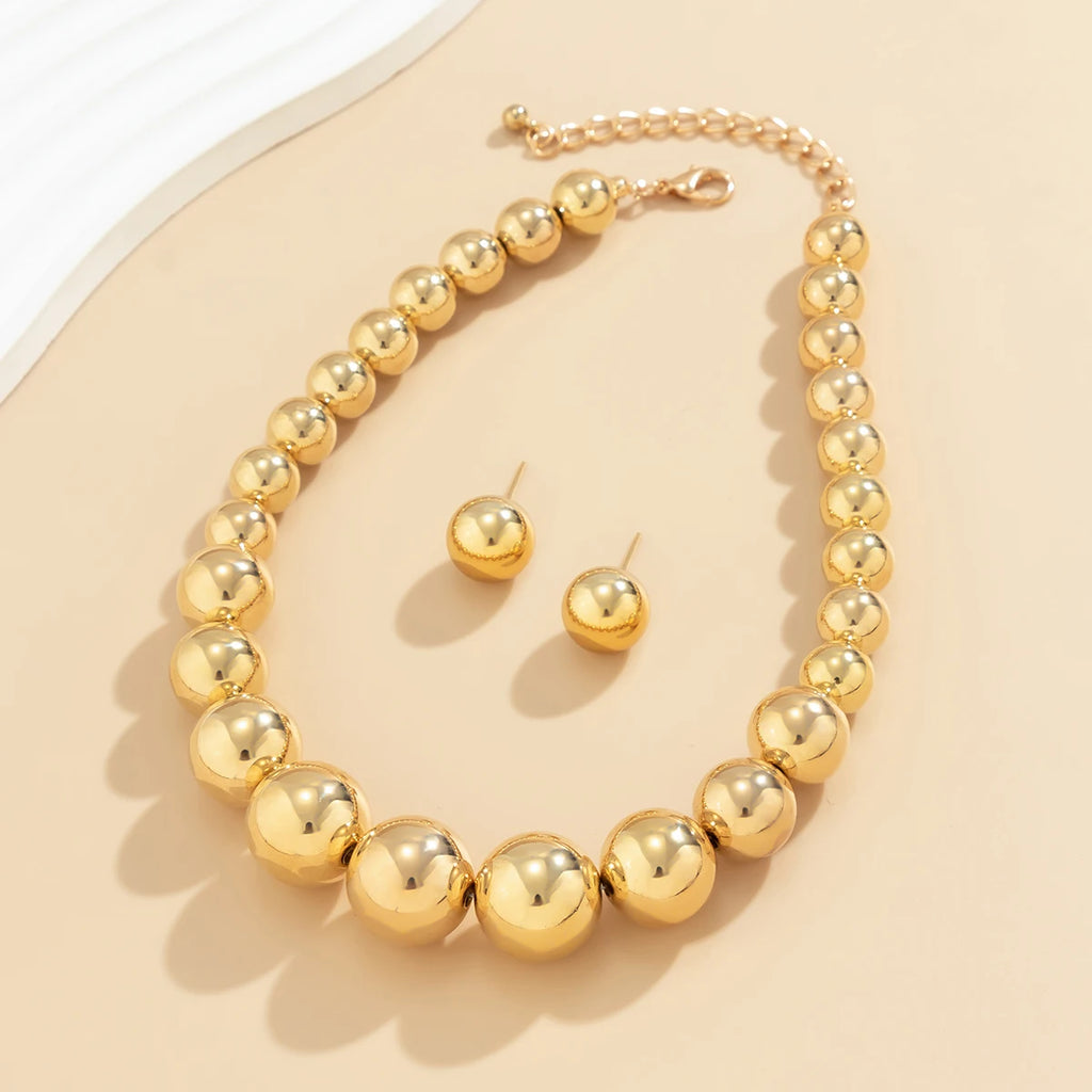 Gold necklace and earrings set on a beige background
