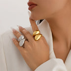 Close-up of a hand wearing gold and silver rings on a neutral background