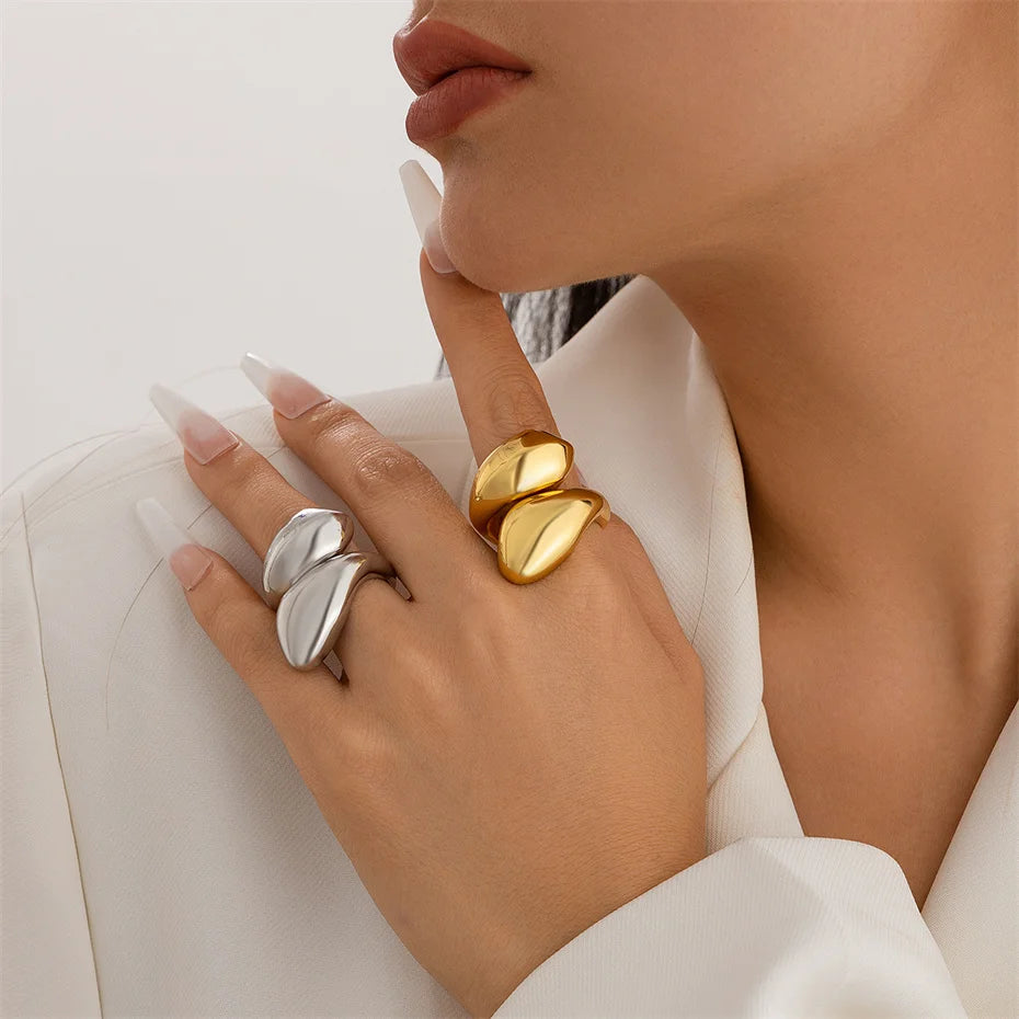 Close-up of a hand wearing gold and silver rings on a neutral background