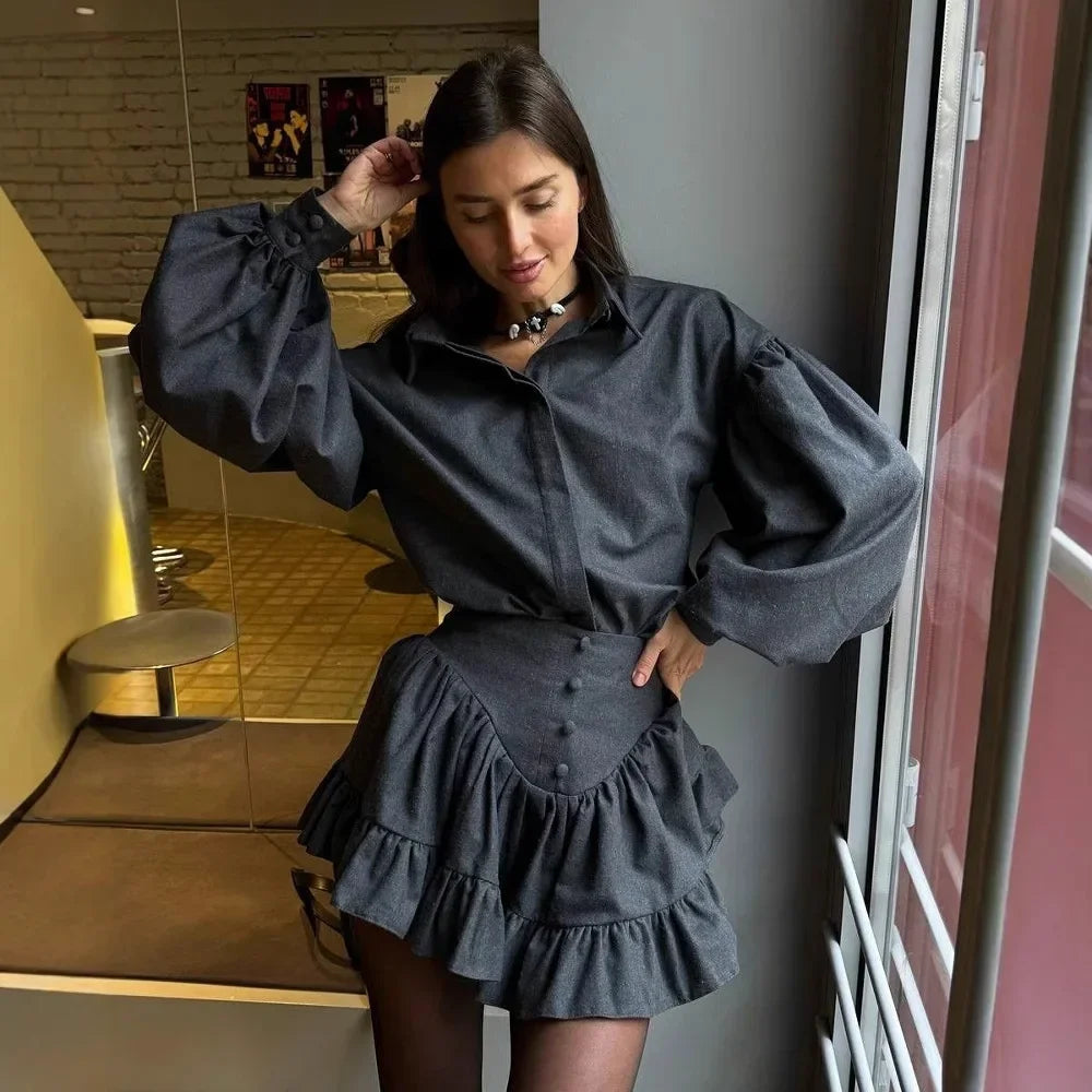 Woman wearing a dark gray outfit with puffed sleeves in an indoor setting.