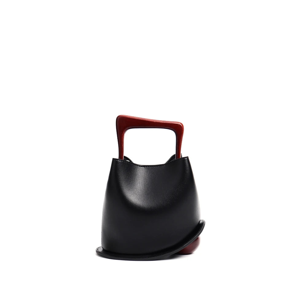 Black handbag with a red handle on a white background