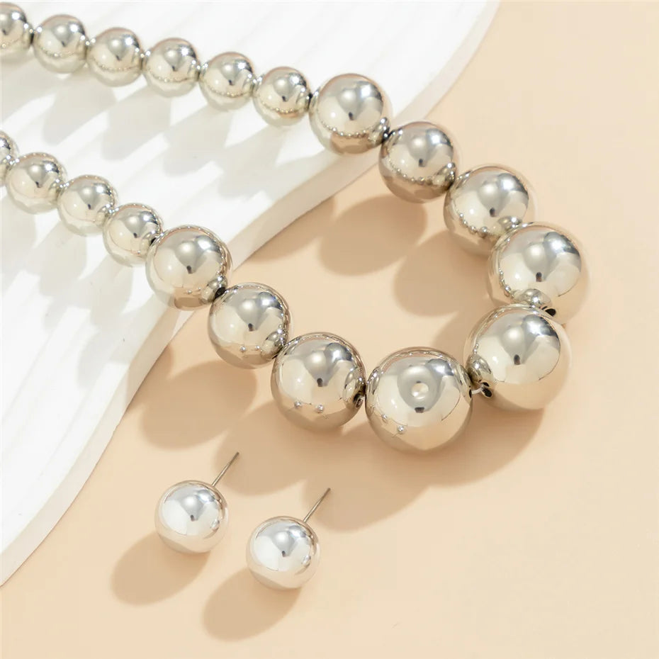 Silver beaded bracelet and earrings on a beige surface