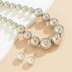 Silver beaded bracelet and earrings on a beige surface