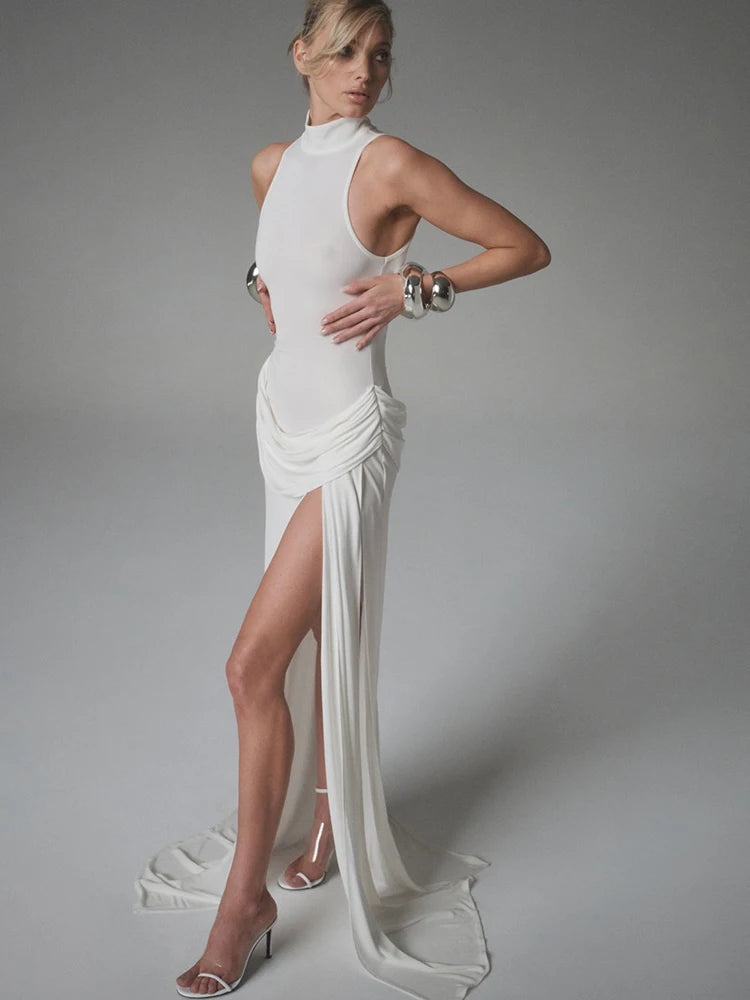 Woman wearing a white evening gown with a high slit on a gray background