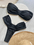 Black bikini set on a textured surface with a woven mat