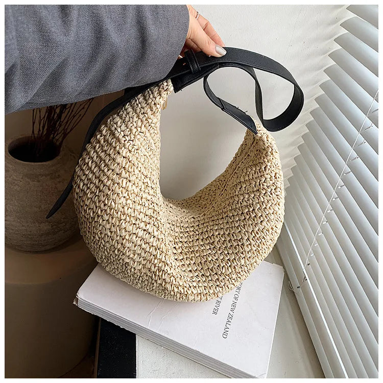 Woven handbag held by a person with a minimal background