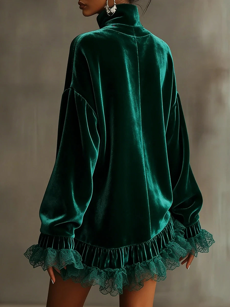 A woman wearing a dark green velvet turtleneck top with long sleeves and a ruffled lace hem, shown from the back against a neutral gray background.