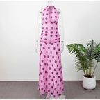 Pink polka dot dress on a mannequin with a plant in the background