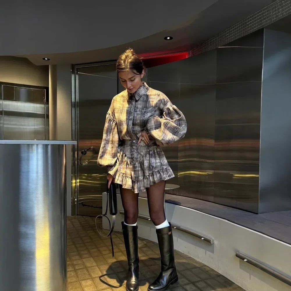 Woman in a plaid outfit standing in a modern interior setting