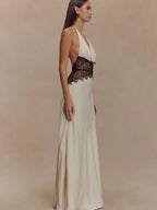 Woman wearing a white evening gown with black lace details on a beige background