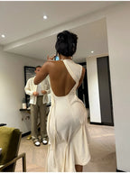 Woman in a white dress taking a photo of a man in a room.