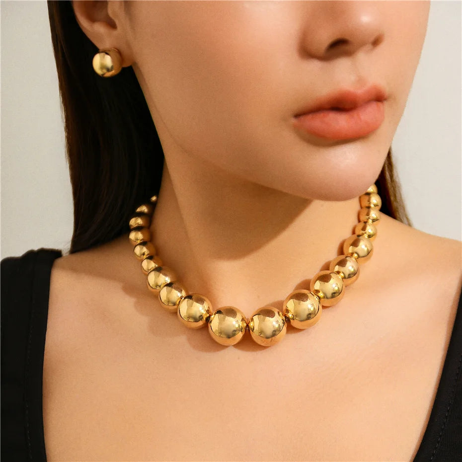 Gold necklace and earrings on a model against a neutral background