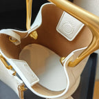 Close-up of a beige handbag with gold accents on a dark background