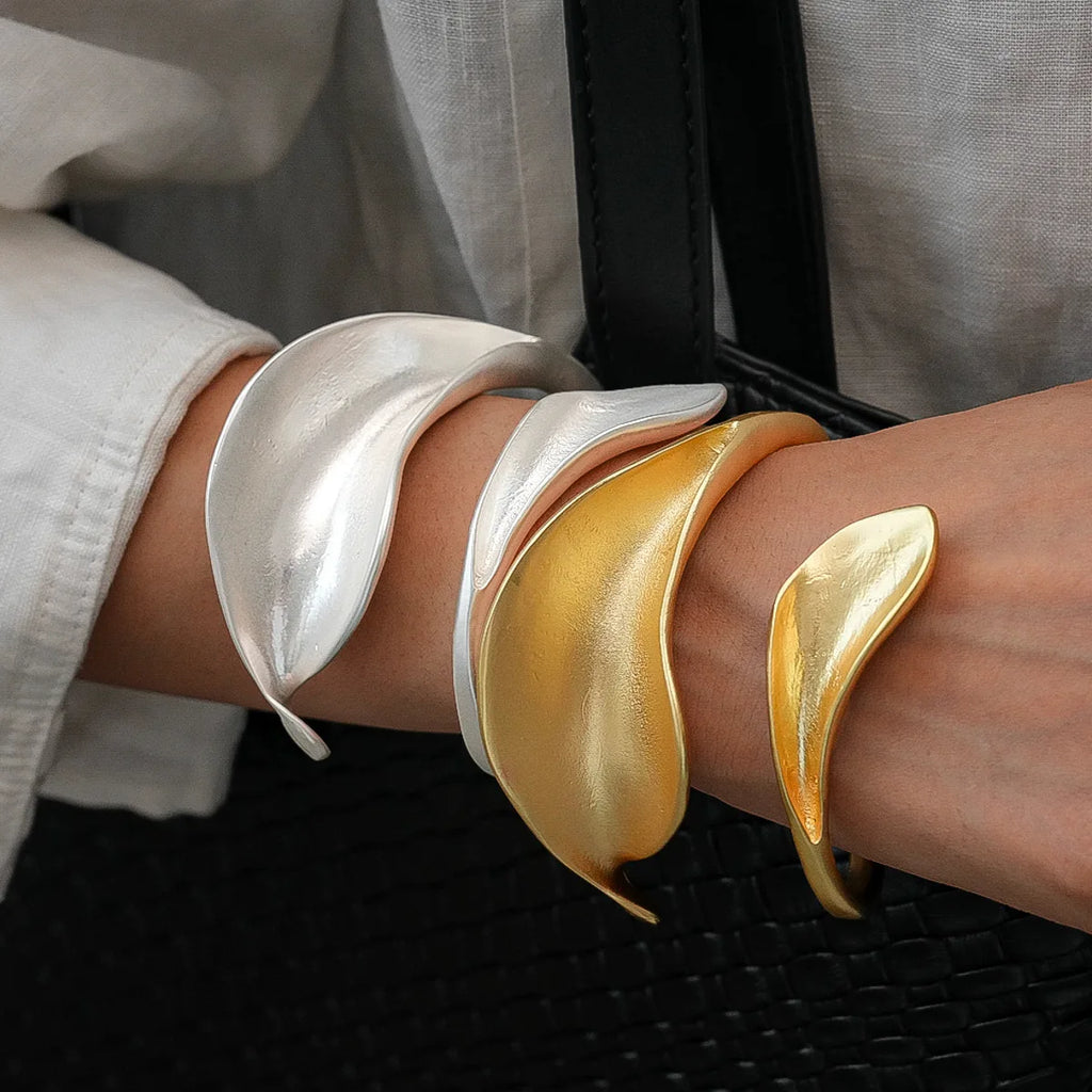 Two metallic bracelets, one silver and one gold, on a person's wrist.