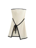 A white strapless mini dress with a solid backless design above knee, featuring a black belt.