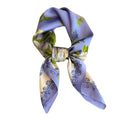 A multicolored floral patterned silk scarf tied in a knot, primarily in shades of blue and white.