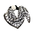 A black and white checkered silk scarf wrapped around a headband, featuring a floral accent on the top corner.