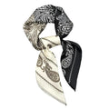 A scarf with a paisley pattern, featuring black and white colors, draped over a white background.
