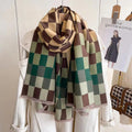 A cashmerette scarf with a woodland check pattern, draped over a white coat on a hanger, with a tag showing 'The Gentlewoman'.