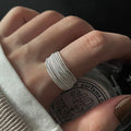 A sterling silver adjustable lines ring on a person's finger, with an irregular shape and pattern, shown in a close-up setting.